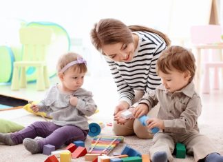 Image: A babysitter watches two toddlers play