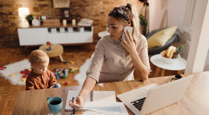 Image: A mom working from home while her toddler plays beside her