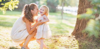 Image: A mom plays with her toddler-aged daughter outdoors during summertime