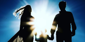 Image: A silhouette of a family holding hands against a blue sky