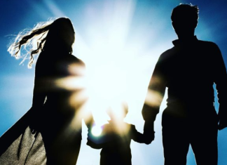 Image: A silhouette of a family holding hands against a blue sky