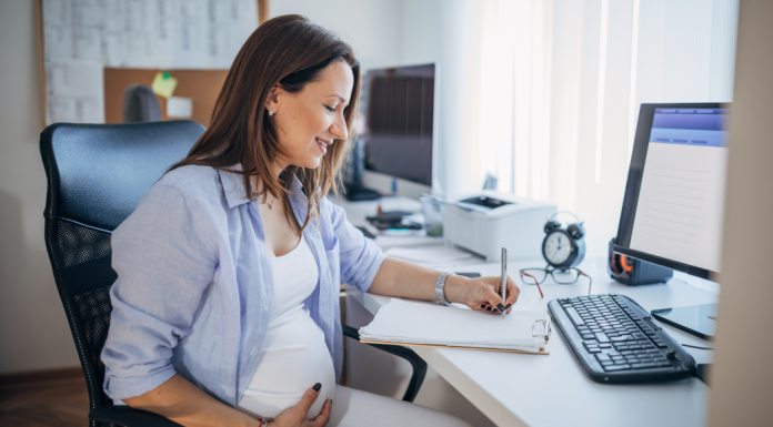 Image: An expectant mother sits at her desk at work