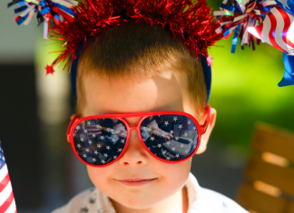 Image: A child wearing 4th of July themed sunglasses and holding flag-themed props