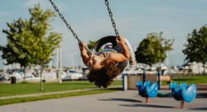 Image: A little girl in a toddler swing at a playground