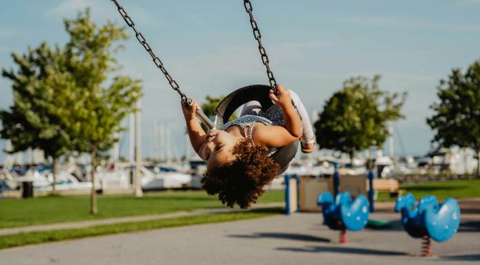Image: A little girl in a toddler swing at a playground