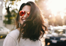 Image: A confident woman wearing sunglasses and smiling as she crosses the street