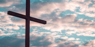 5 Simple, Meaningful Ways to Share the Gospel With Your Kids Image: A large cross silhouetted against a cloudy daytime sky