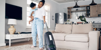Image: A mom vacuums while holding a toddler