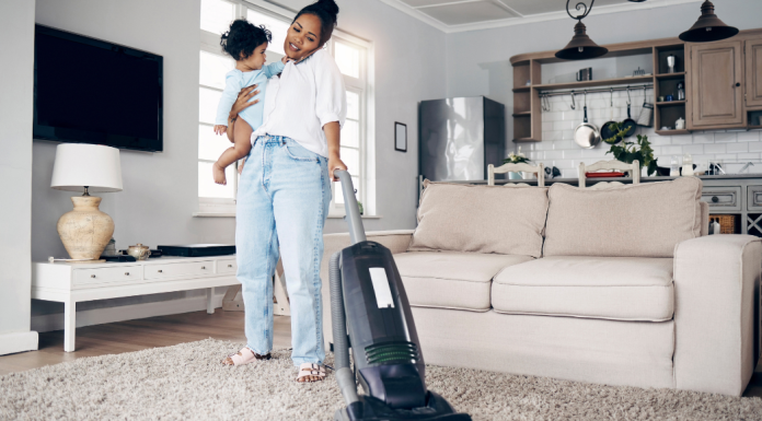 Image: A mom vacuums while holding a toddler
