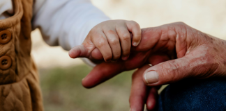 Image: A toddler's hand holding onto their grandparent's hand